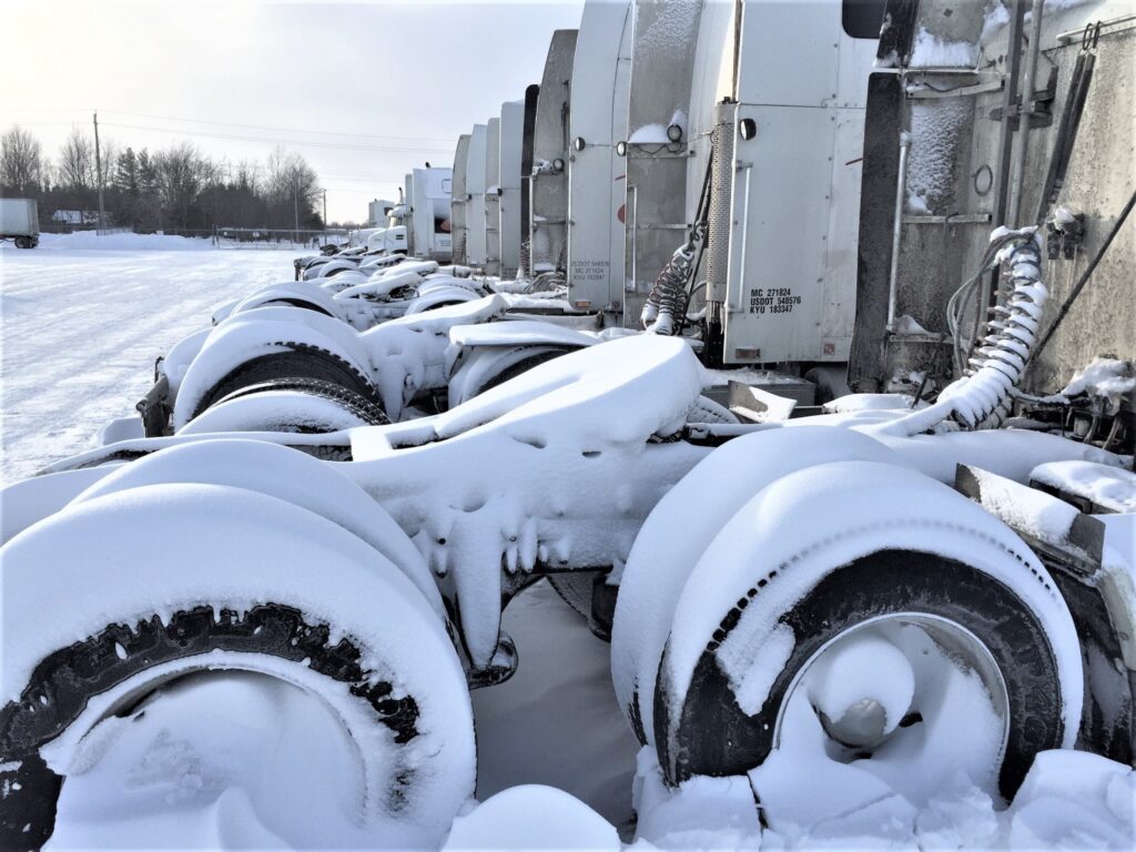 A line of parked trucks covered in a large amount of snow