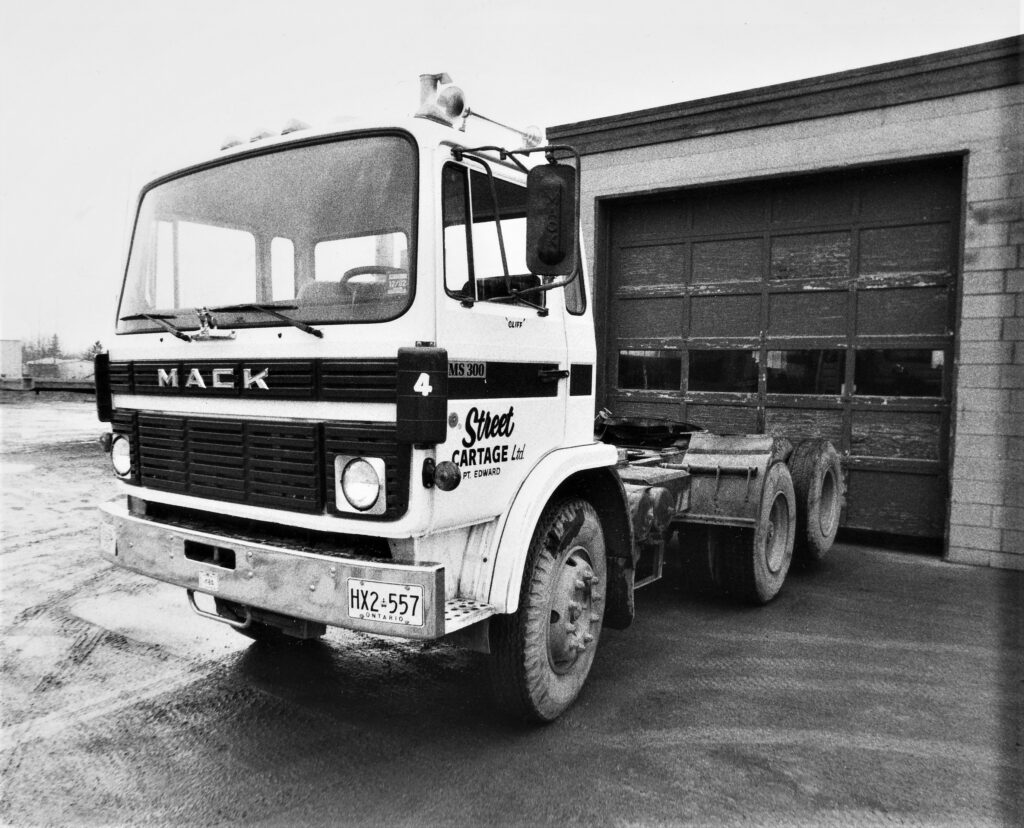 Old Mack truck parked in front of garage